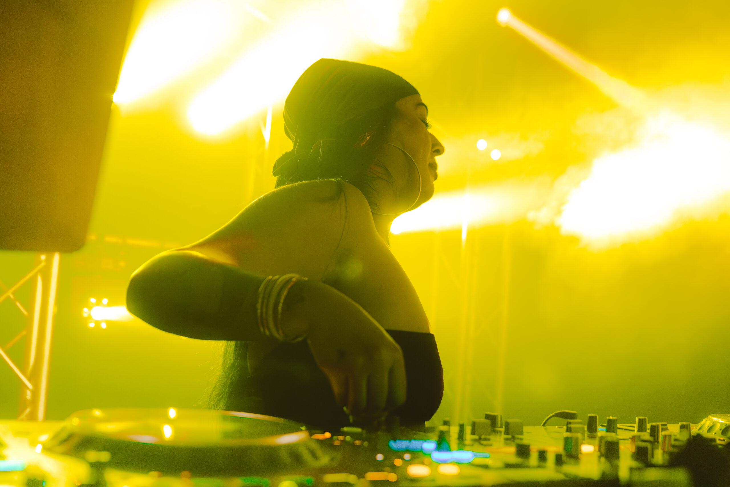 DJ in fel geel licht achter de draaitafels