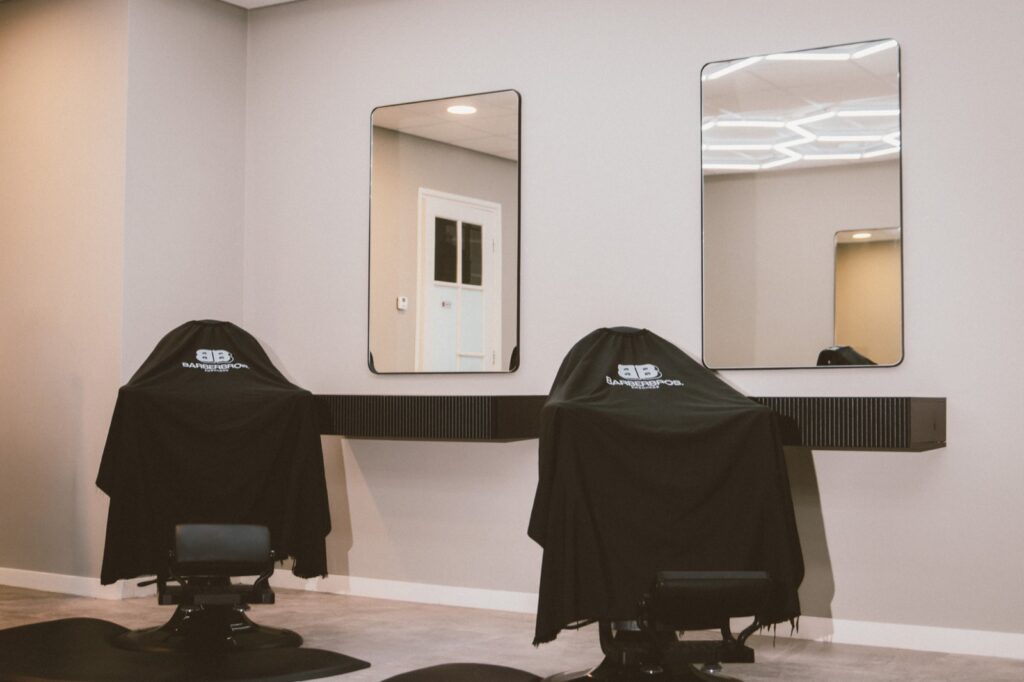 Twee kappersstoelen met BarberBros-capes voor de spiegels