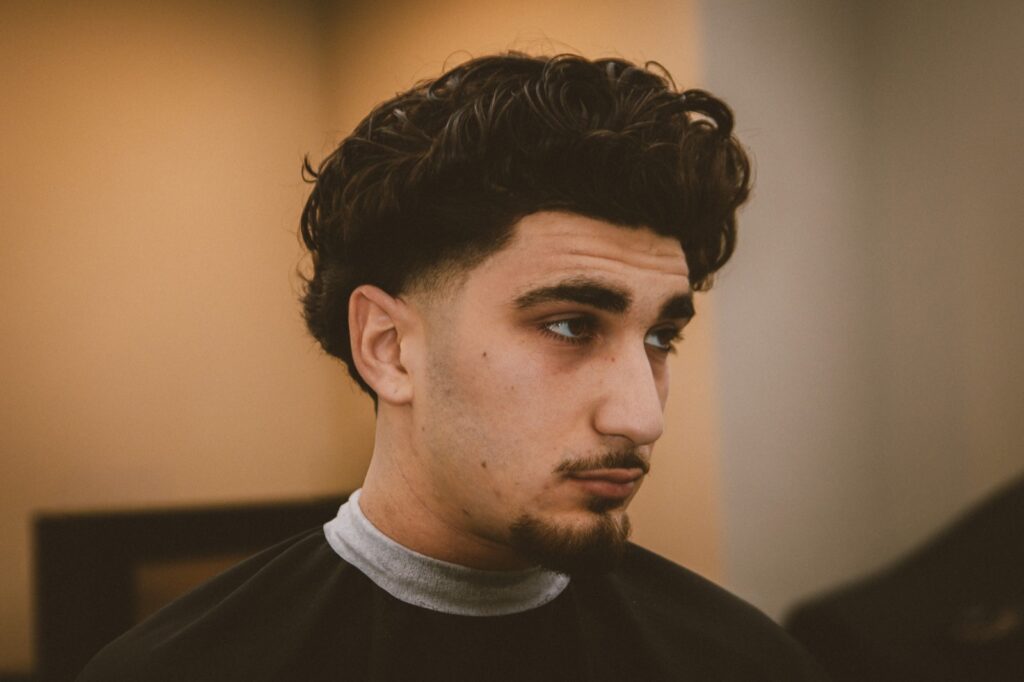 Klant met krullen en een strakke fade na de knipbeurt