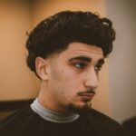 Klant met krullen en een strakke fade na de knipbeurt