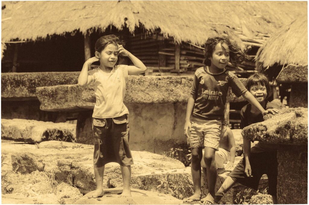 Kinderen spelen tussen traditionele stenen graven op Sumba