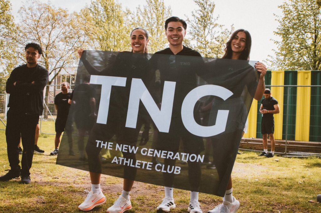 Drie lachende leden houden de TNG-vlag vast