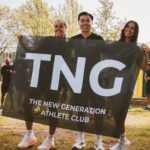 Drie lachende leden houden de TNG-vlag vast