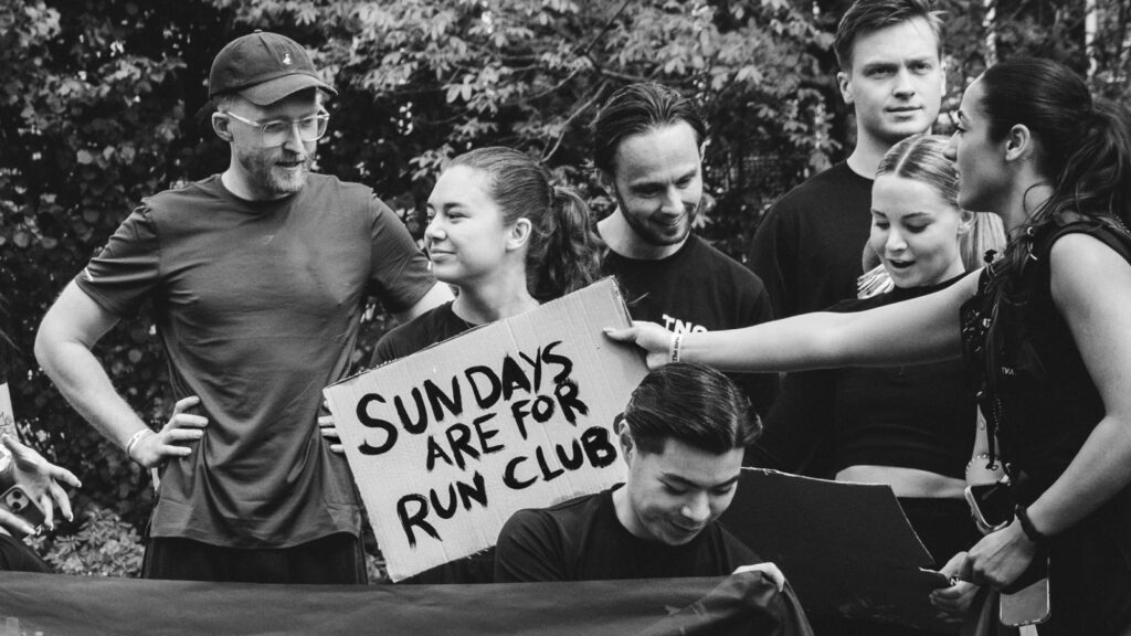 Zwart-witfoto van de groep met het bord Sundays are for run clubs