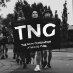 Zwart-witfoto van lopers met de TNG-vlag voorop