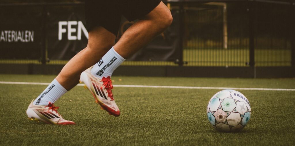 Benen en voetbalschoenen bij de bal