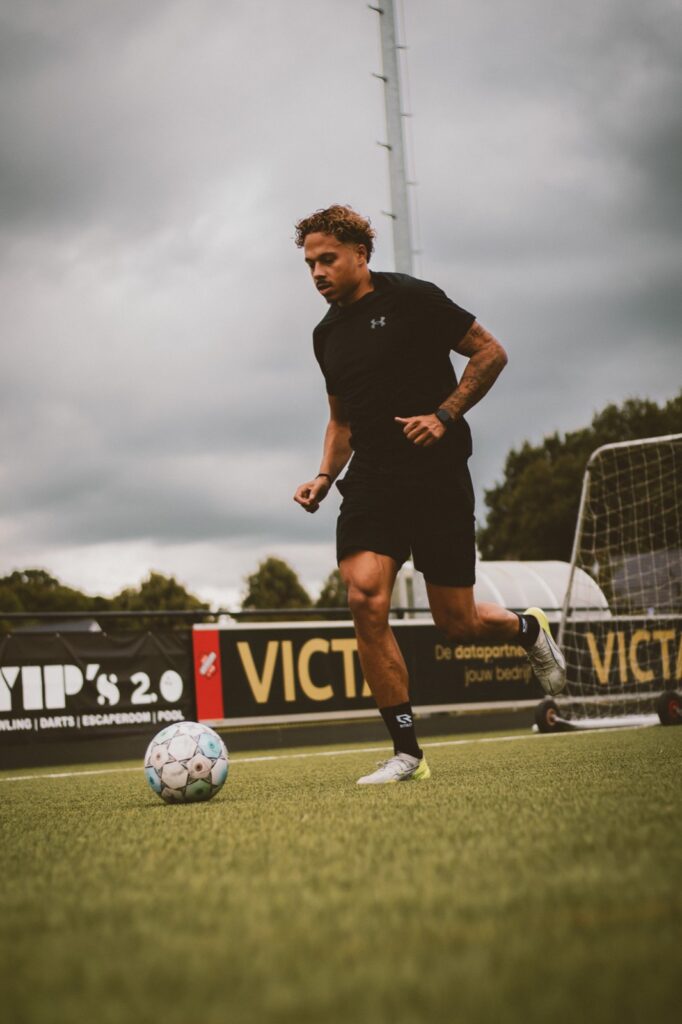 Speler dribbelt met de bal langs de reclameborden